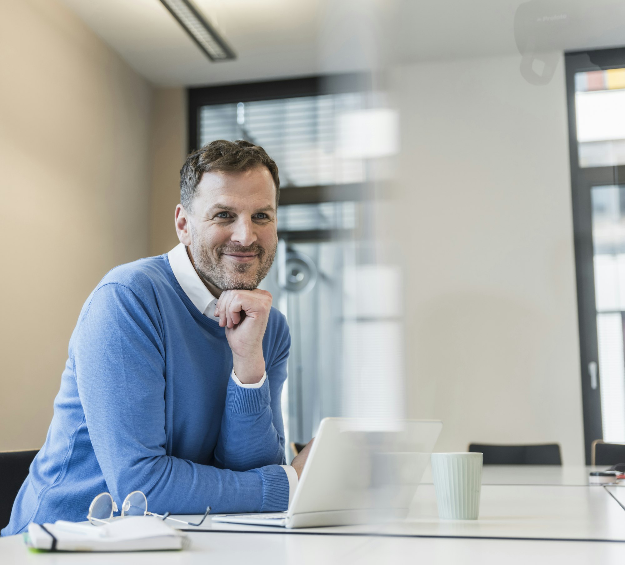 Portrait of smiling businessman with laptop in office