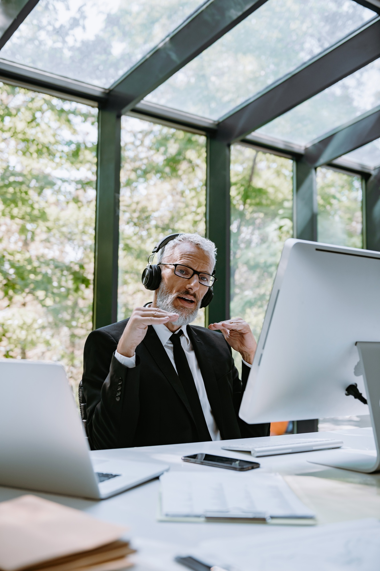 Mature businessman in headphones using computer while having video conference from office